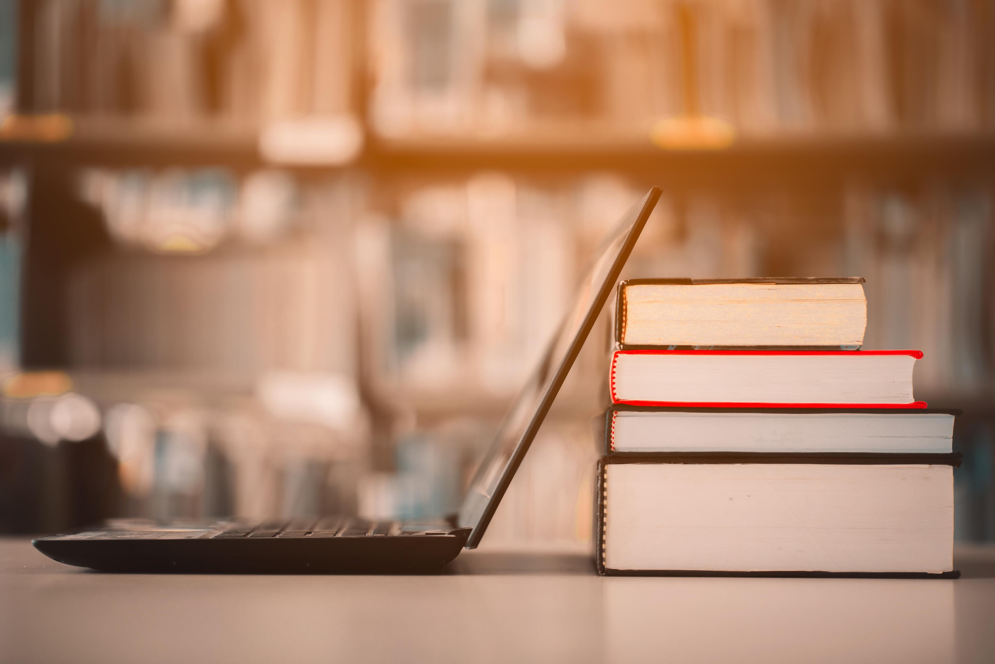 Boeken naast een laptop in een bibliotheek